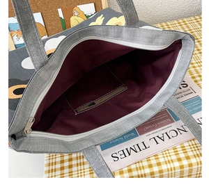 Interior view of grey canvas tote bag with zipper pocket and purple lining details