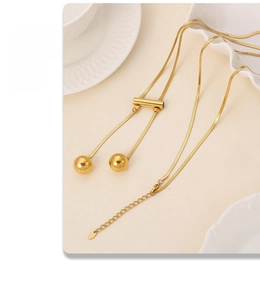 Detail of adjustable 18K gold-plated snake chain necklace with dual ball pendants