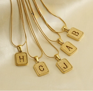 Detail of five 18K gold-plated stainless steel snake chains with square letter pendants
