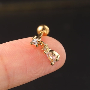 Macro shot of gold droplet zircon stud earring on fingertip showing precise size detail