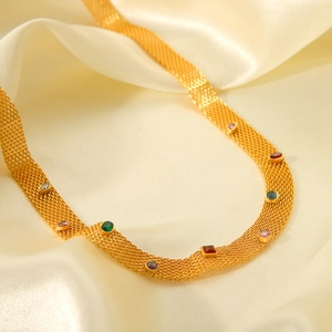 Close-up of golden mesh chain necklace featuring vibrant multi-colored gemstones on silk