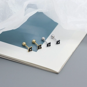 Macro detail of gold and silver four-leaf clover screw back earrings with black zircons