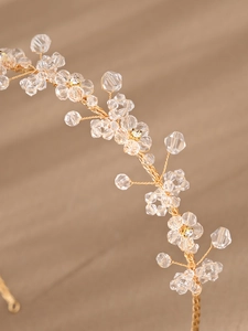 Close-up of handmade gold wire headband with clear crystal beads and floral patterns