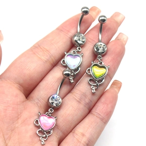 Detailed close-up of devil heart belly rings with pink blue yellow gradient pendants