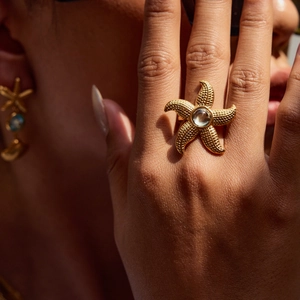 Detail of golden starfish ring with clear gemstone and matching beach style earrings