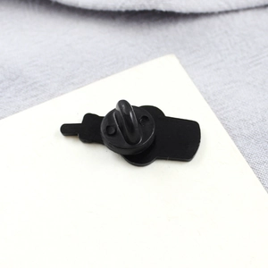 Close-up of black rubber pin clutch and badge backing on a minimalist cardboard base
