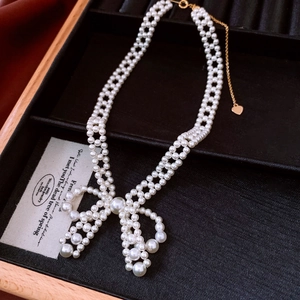 Detailed view of pearl necklace with bow pendant in a premium velvet display box