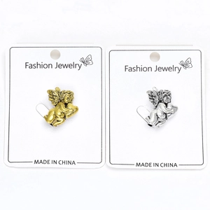 Macro detail of retro alloy angel cupid brooches in gold and silver finishes on cards