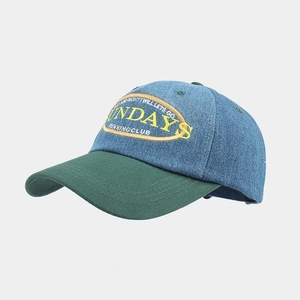 Detail of blue denim baseball cap with green brim and yellow embroidery patch