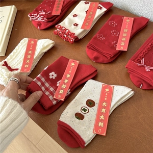Festive red and white cotton crew socks with ruffles and bows on a wooden table