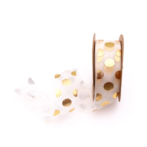 Detail of white organza ribbon with gold foil dots on a brown kraft paper spool