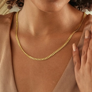 Detailed close-up of an 18k gold plated Cuban link chain necklace on a female model