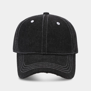 Detail of black denim baseball cap showing white contrast stitching on curved brim