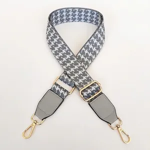 Close-up of gray houndstooth bag strap with adjustable gold buckle and leather accents
