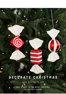Detail of red and white striped candy Christmas ornaments on a tree with warm lights