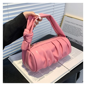 Pink ruched cloud bag with knotted handle detail shown against aesthetic backdrop