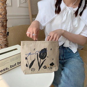 Close-up of beige canvas makeup bag with black tulip embroidery and sturdy texture