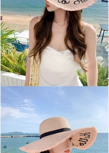 Detail of light beige wide brim straw hat with black ribbon and elegant embroidery