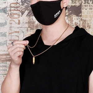 Close-up of a gold bullet pendant necklace worn by a male model in streetwear style
