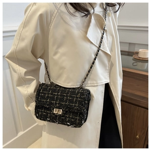 Detailed view of black tweed chain bag with gold metal buckle and woven texture