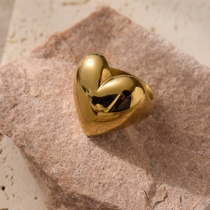 Polished 18K gold-plated chunky heart-shaped ring displayed on a natural stone base