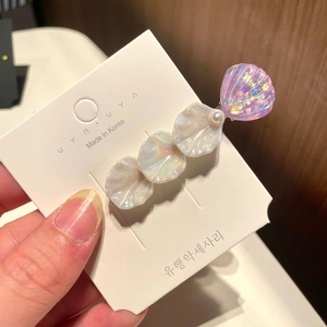 Detailed view of mermaid style hair clip with iridescent shell charms and a small pearl