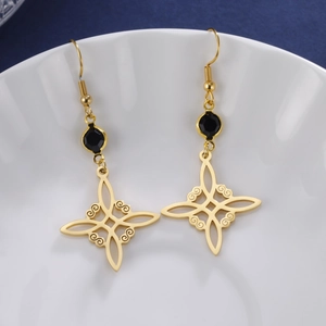 Gold Celtic knot earrings with black rhinestones on a white ceramic tray