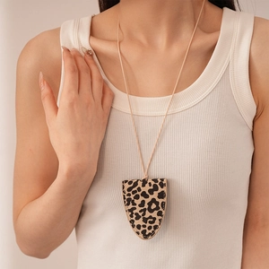Detail of leopard print leather clochette necklace with fine hand-stitched edging on apparel