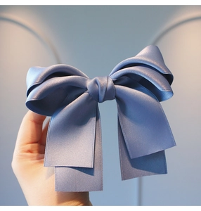 Detailed close-up of a large multi-layered foggy blue satin bow hairclip for girls