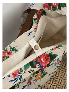 Detail of vintage floral canvas tote bag featuring bronze snap button closure and red flowers
