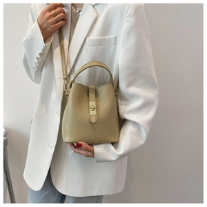 Detailed view of beige PU leather bucket bag featuring gold metal lock and detachable strap