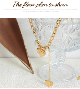 Detail of 18K gold-plated double heart pendant necklace on textured glass rim