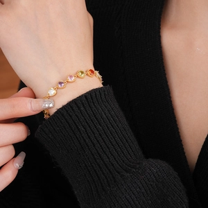 Close-up of gold chain bracelet with colorful round zircons worn on female wrist
