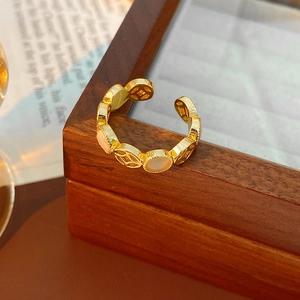 Détail macro d'une bague chaîne dorée avec incrustations de nacre et motifs de paix