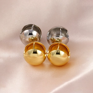 Detail of high-polished gold and silver ball hoop earrings on soft pink satin fabric