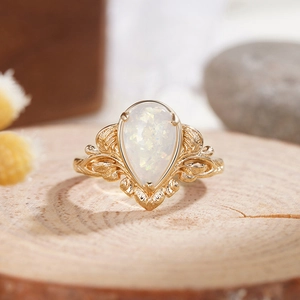 Detailed view of pear-cut opal ring with golden leaf engraving and vintage texture