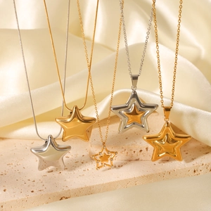 Detailed shot of gold and silver star pendant necklaces on a stone and satin backdrop