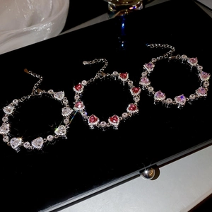 Close-up of heart-shaped zircon bracelets in white, red and pink stones on black background