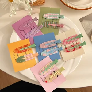 Detail of colorful fruit pattern hair clips set on display card with cherry and peach icons
