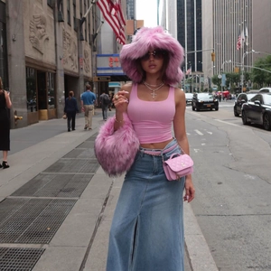 Detail of pink faux fur hat and luxury chain waist bag in a trendy street style look