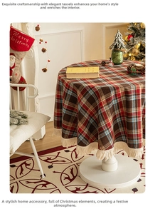 Close-up of red and green plaid round tablecloth with cream tassels for Christmas decor