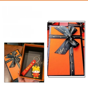 Detailed view of orange gift box with black ribbon and cute tiger keychain accessory