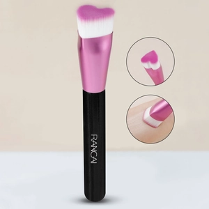 Detail of heart-shaped makeup brush with pink gradient bristles and black handle