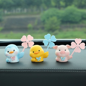 Cute cartoon penguin duck and pig car ornaments with clover windmills on a dashboard