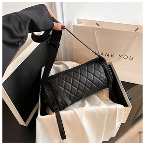 Detail einer schwarzen gesteppten Zylindertasche in einer Geschenkbox mit Tüte