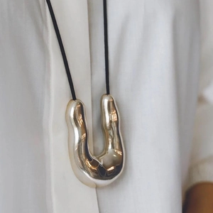 Elegant minimalist irregular U-shape polished metal pendant necklace on white shirt
