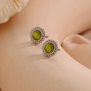 Macro shot of silver beaded earrings with green cat-eye stone in vintage style