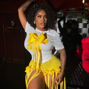 Détail du t-shirt blanc avec grand nœud jaune et short en dentelle avec pompons ruban