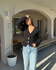 Detailed view of black V-neck knit cardigan with unique gold decorative sun buttons