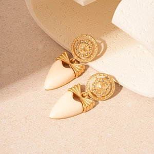 Boucles d'oreilles vintage avec pendentif cœur doré et strass sur un support beige
